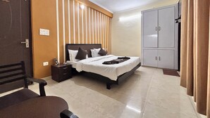 A hotel room with a bed, nightstand, wardrobe, and a ceiling fan. - Beautiful 1-bedroom hotel with AC in peaceful Rishikesh (Rishikesh)