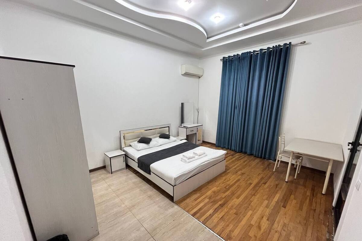 A bedroom with a bed, bedside tables, a desk, and a chair.