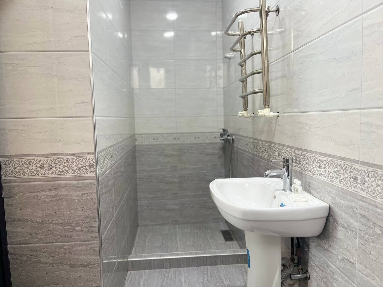 A bathroom with a shower, a sink, and a towel rack.
