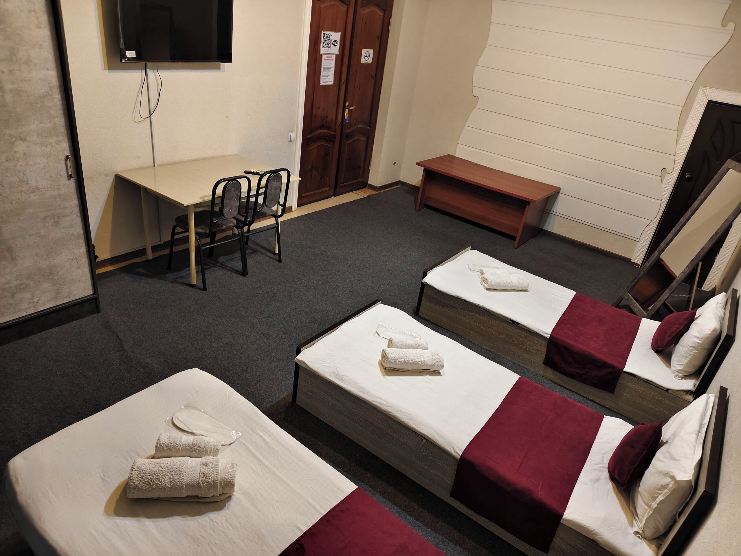 A hotel room with two single beds, a desk, a chair, and a TV.