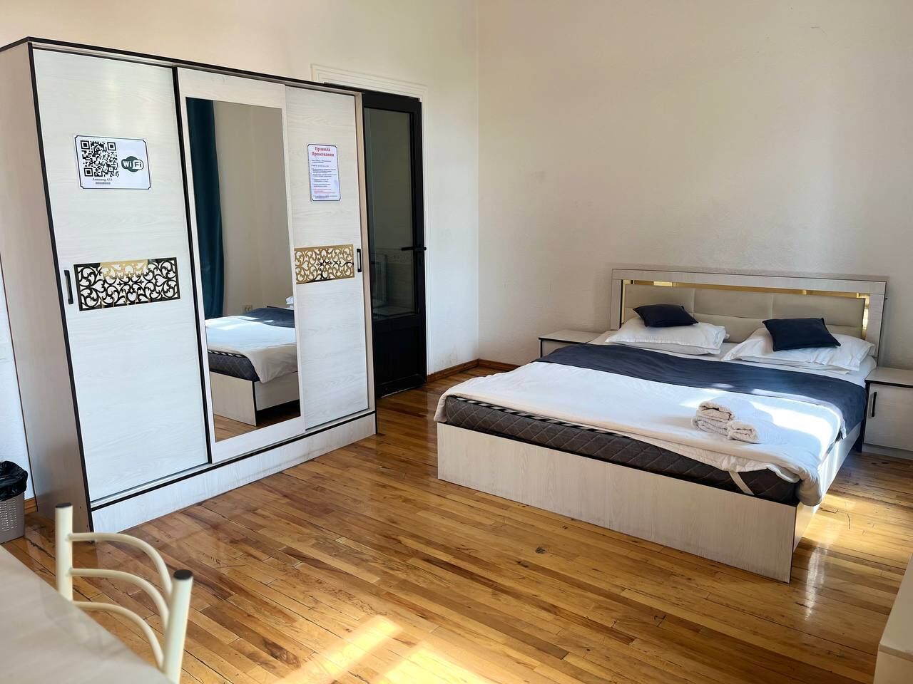 Une chambre à coucher avec un lit, une armoire, un miroir et un plancher en bois.
