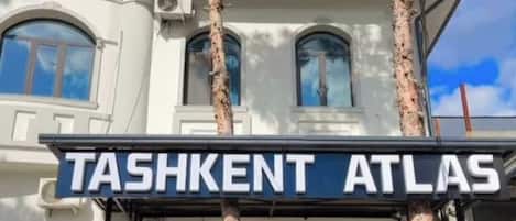 A two-story building with a sign reading 'TASHKENT ATLAS.'