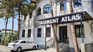 A building with a sign reading 'TASHKENT ATLAS' and a white car parked in front. - Tashkent Atlas  (Tashkent)