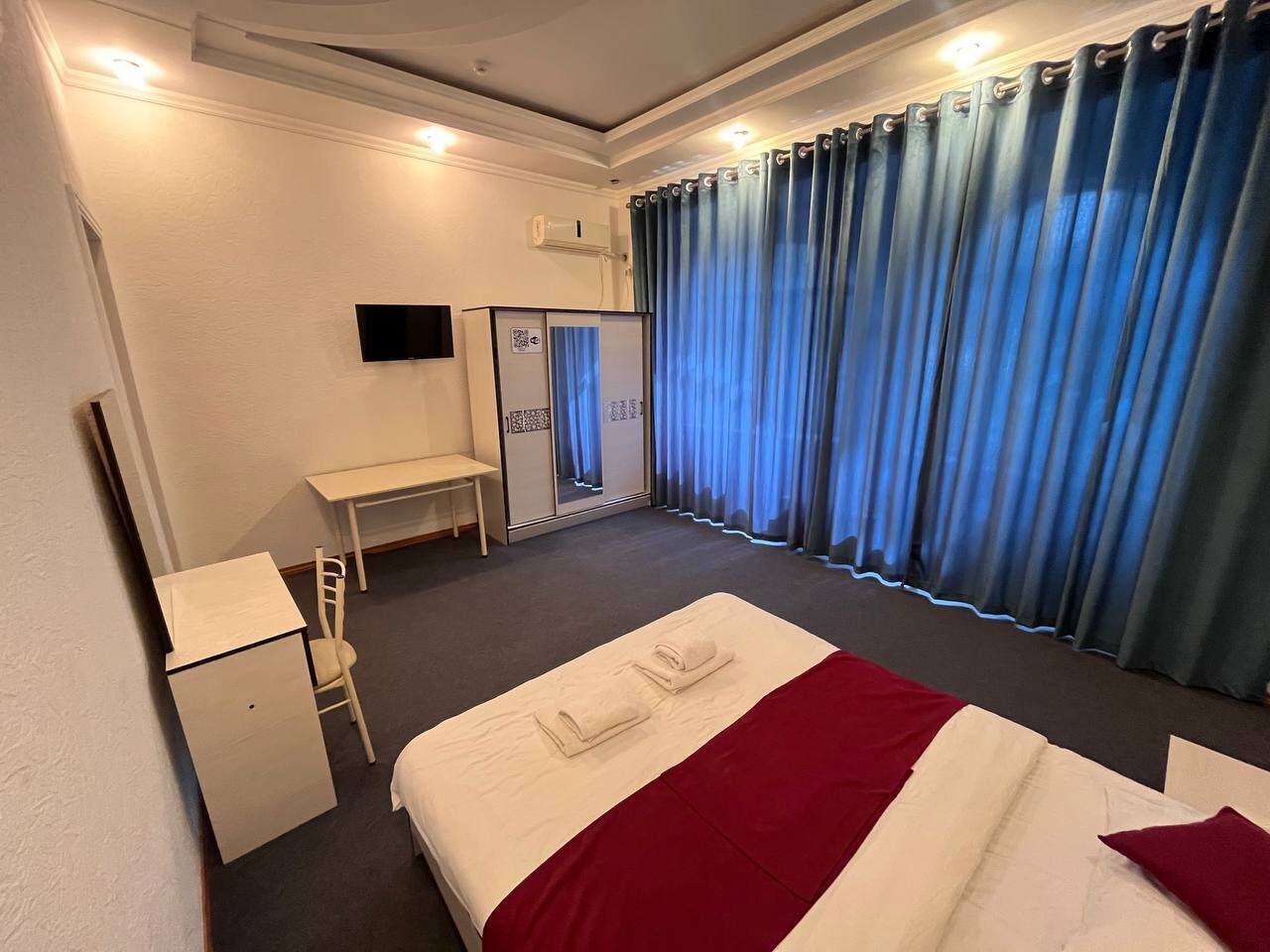 Habitación de hotel con cama, escritorio, silla, armario y televisor.