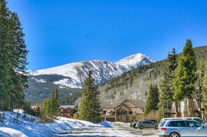 A mountain lodge with a snow-covered peak, surrounded by evergreen trees and a clear blue sky. - Breckenridge Area Condo w/ Mountain Views (Breckenridge)