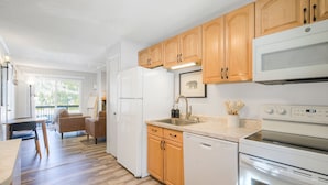 Una cocina moderna con armarios de madera, un refrigerador blanco, lavavajillas y horno empotrado.