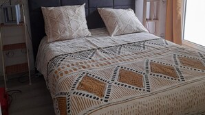 A bedroom with a bed, headboard, pillows, bedside table, lamp, and a window with curtains. - T2 APARTMENT ON 1ST FLOOR 200 M FROM GRANDE PLAGE AND SHOPS (Saint-Cast-le-Guildo)