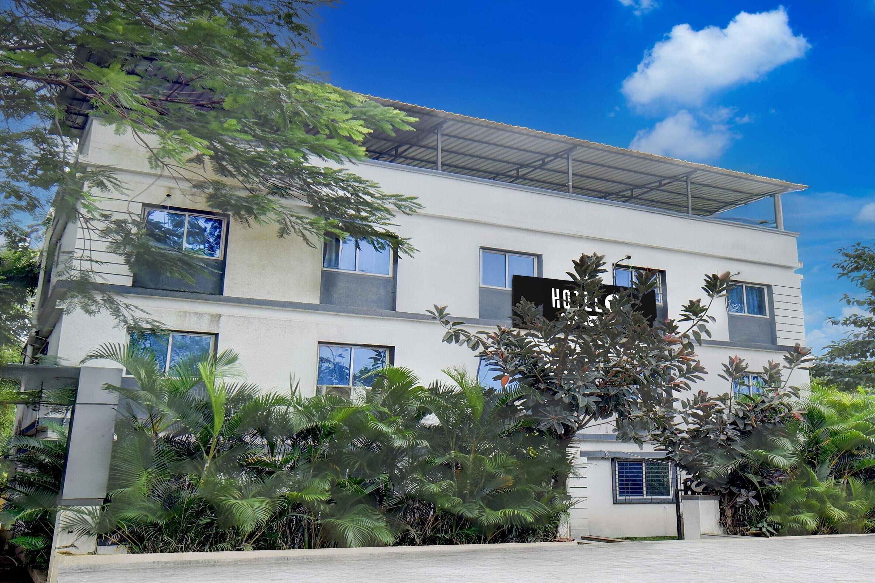 A modern multi-story building with a flat roof, large windows, and a sign that reads 'HOTEL.'