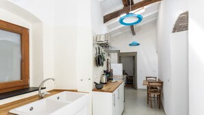 Une cuisine moderne avec un évier blanc, un plan de travail en bois et un coin repas comprenant une table et des chaises.