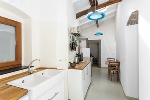 Eine moderne Küche mit einer weißen Spüle, einer Holz Arbeitsplatte und einem Essbereich mit Tisch und Stühlen.