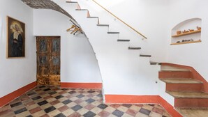 Un escalier avec une rampe en bois, un sol à carreaux et une porte avec un cadre en bois.