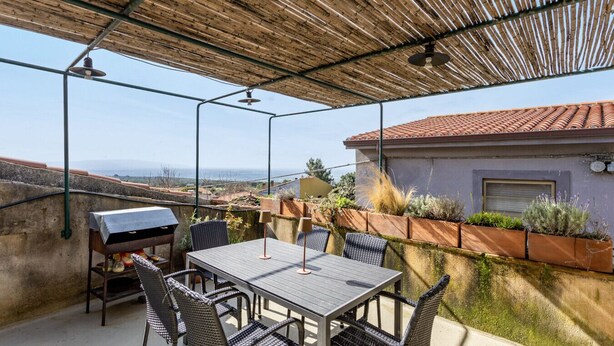 Une terrasse extérieure avec une table et des chaises, un barbecue et une vue sur le paysage.