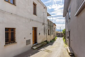 Eine enge Straße mit Gebäuden an beiden Seiten, einer sichtbaren Tür und einem klaren Himmel.