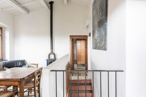 Ein Essbereich mit Holztisch und Stühlen, einem schwarzen Herd, einer Treppe und einem Gemälde an der Wand.