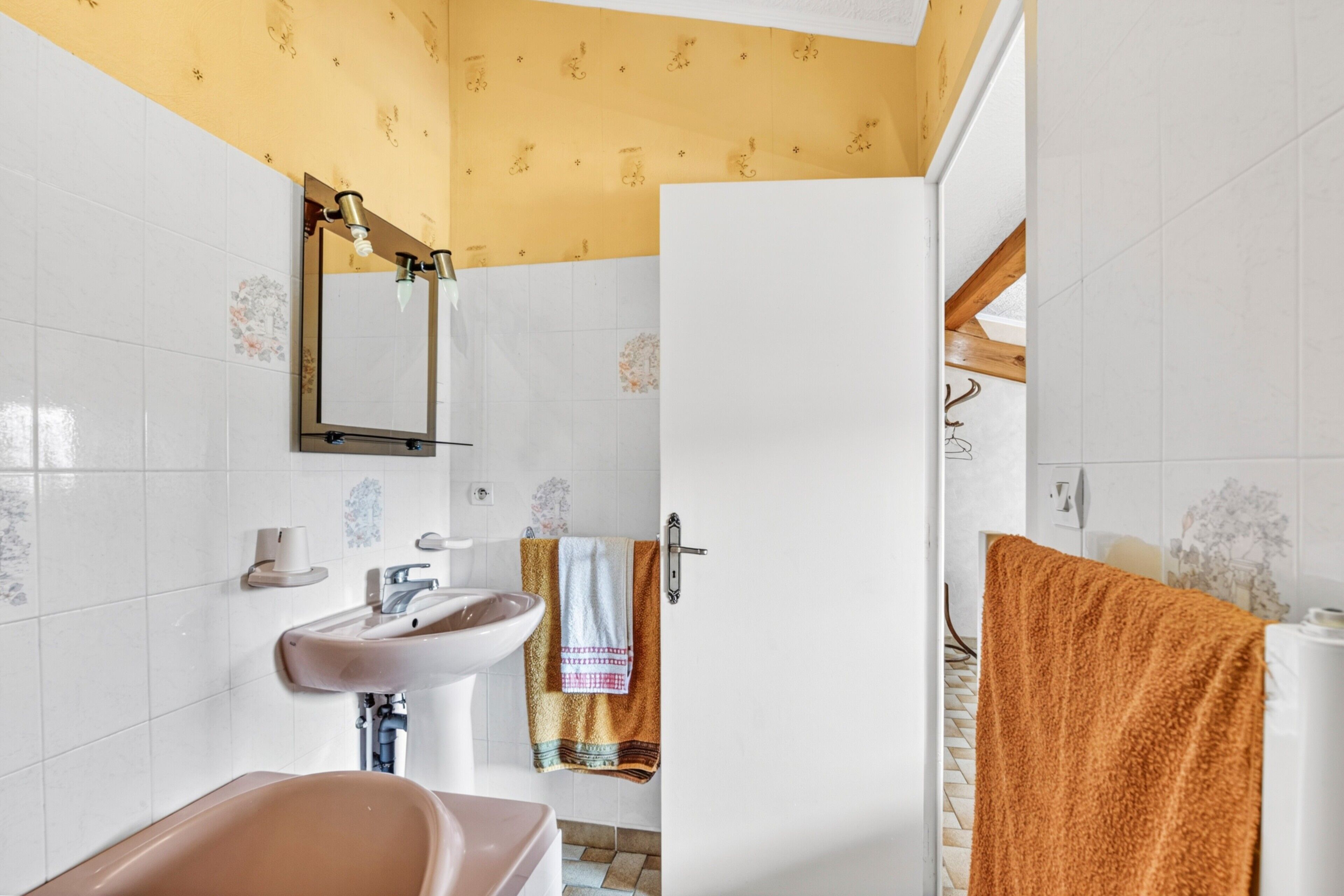 A bathroom with a sink, mirror, and towel rack.