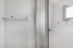 A bathroom with white speckled tiles, a glass shower enclosure, and a small shelf. - Bed and Breakfast 'Chambre Rose' with Mountain View, Shared Terrace and Wi-Fi (Saint-Vérand)