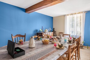 A dining room with a table set for a meal, chairs, a wooden ceiling beam, and a window with curtains. - Bed and Breakfast 'Chambre Rose' with Mountain View, Shared Terrace and Wi-Fi (Saint-Vérand)