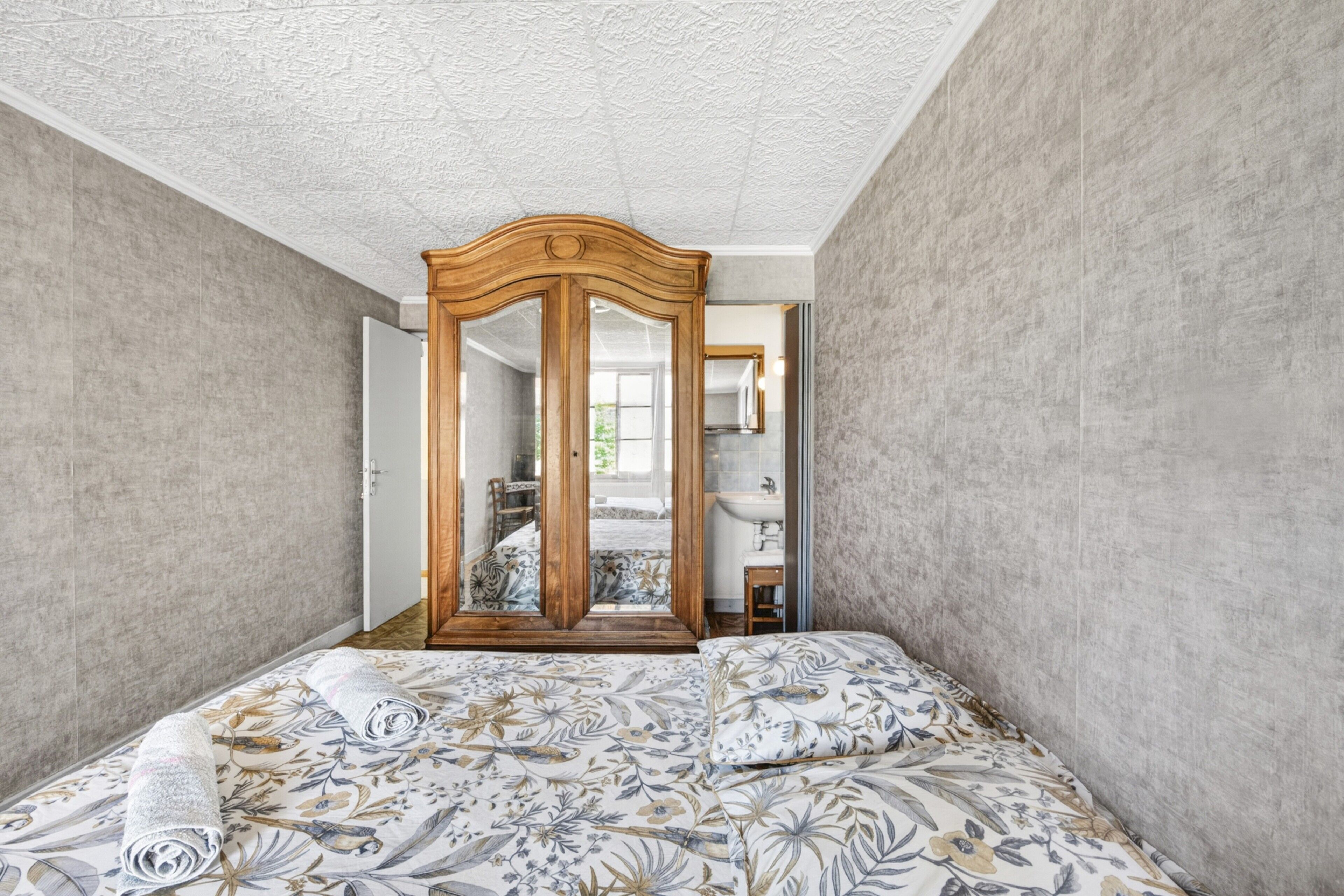 Un dormitorio con una cama, un armario de madera y un espejo.