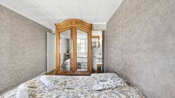 Un dormitorio con una cama, un armario de madera y un espejo.
