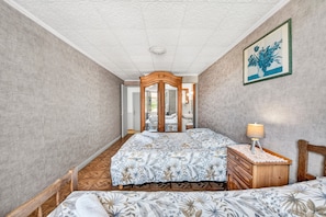 Un dormitorio con cama, cómoda, espejo y una puerta que da a otra habitación.