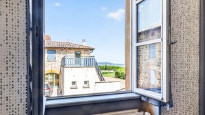 Une vue par la fenêtre sur un immeuble doté d’un balcon, d’un radiateur et d’un mur orné de motifs.