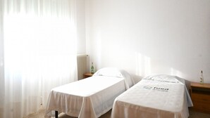 A room with two single beds, a radiator, a bottle on a nightstand, and sheer curtains. - SE235 - Senigallia, large three-room apartment with furnished courtyard (Roncitelli)