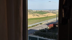A view from a window overlooking a road with fields and a distant town. - SE235 - Senigallia, large three-room apartment with furnished courtyard (Roncitelli)