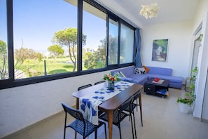 A modern living room with a dining area, large windows, a sofa, and a coffee table.