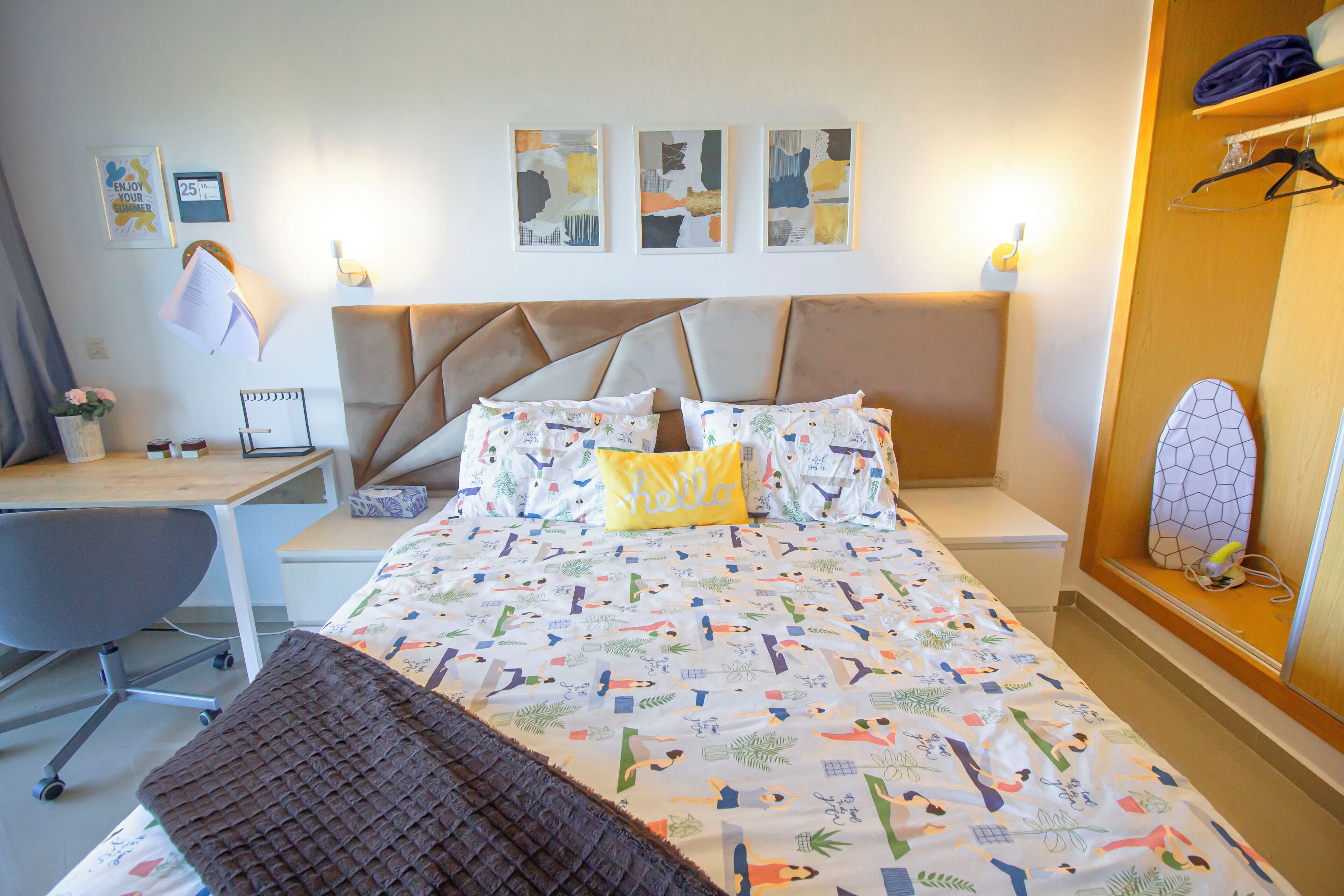 Een slaapkamer met een bed, bureau, stoel en nachtkastje.