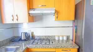 Una cocina con armarios de madera, un refrigerador de acero inoxidable, un horno empotrado y una encimera de granito.