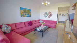 Una sala de estar con un sofá rosa, una mesita de centro y un cuadro en la pared.