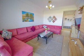 A living room with a pink sofa, a coffee table, and a painting on the wall.