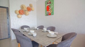 En matplats med ett bord dukat för sex personer, sex grå stolar och dekorativ väggkonst.