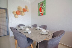 A dining area with a table set for six, six grey chairs, and decorative wall art.