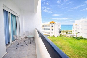 Ein Balkon mit Meerblick, ein weißes Gebäude und eine Rasenfläche.