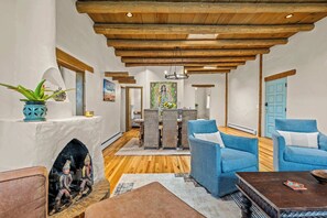 Ein geräumiger Wohnbereich mit Kamin, blauen Polstersesseln, Holzboden und einem Esstisch mit Stühlen.
