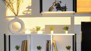 A wall-mounted shelf with a motorcycle, potted plants, and books. - Luxury Apartment Sunset – Private Parking (Tanger)