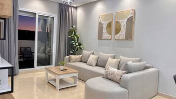 Un salon moderne avec un canapé, une table basse, une plante en pot et une vue à travers une porte vitrée.