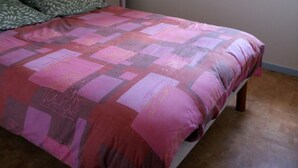Une chambre à coucher comprenant un lit, une armoire, une fenêtre et un luminaire suspendu.