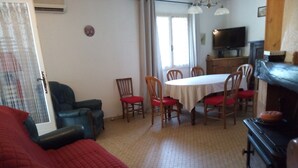 Un salon avec un canapé rouge, une table à manger avec des chaises, un téléviseur et une cheminée.