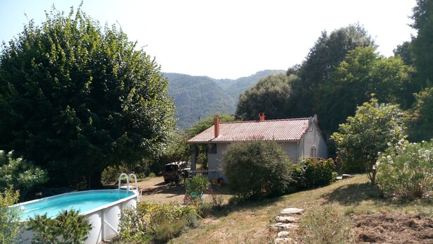 Une maison avec une piscine, entourée d’arbres et de collines.
