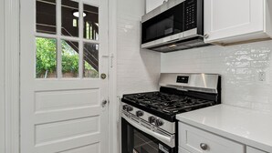 A kitchen with white cabinetry, a gas stove, an oven, and a microwave. - Cozy 1BR1BTH in Old Town Alexandria -Steps From Metro (Alexandria)