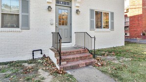A two-story white brick building with a gray front door, a small front porch with steps, and a black metal railing. - Cozy 1BR1BTH in Old Town Alexandria -Steps From Metro (Alexandria)