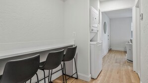 A narrow hallway with a white wall, a wooden floor, and a white door at the end. - Cozy 1BR1BTH in Old Town Alexandria -Steps From Metro (Alexandria)