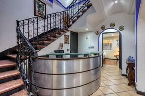Un escalier avec une rampe en métal, un comptoir d’accueil et un sol carrelé.