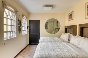 Une chambre avec deux lits, une porte, un miroir et une fenêtre.