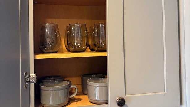 Una cocina con alacenas abiertas, que contiene cristalería y utensilios de cocina.
