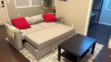 A living room with a sofa, a coffee table, a plant, and a painting on the wall.