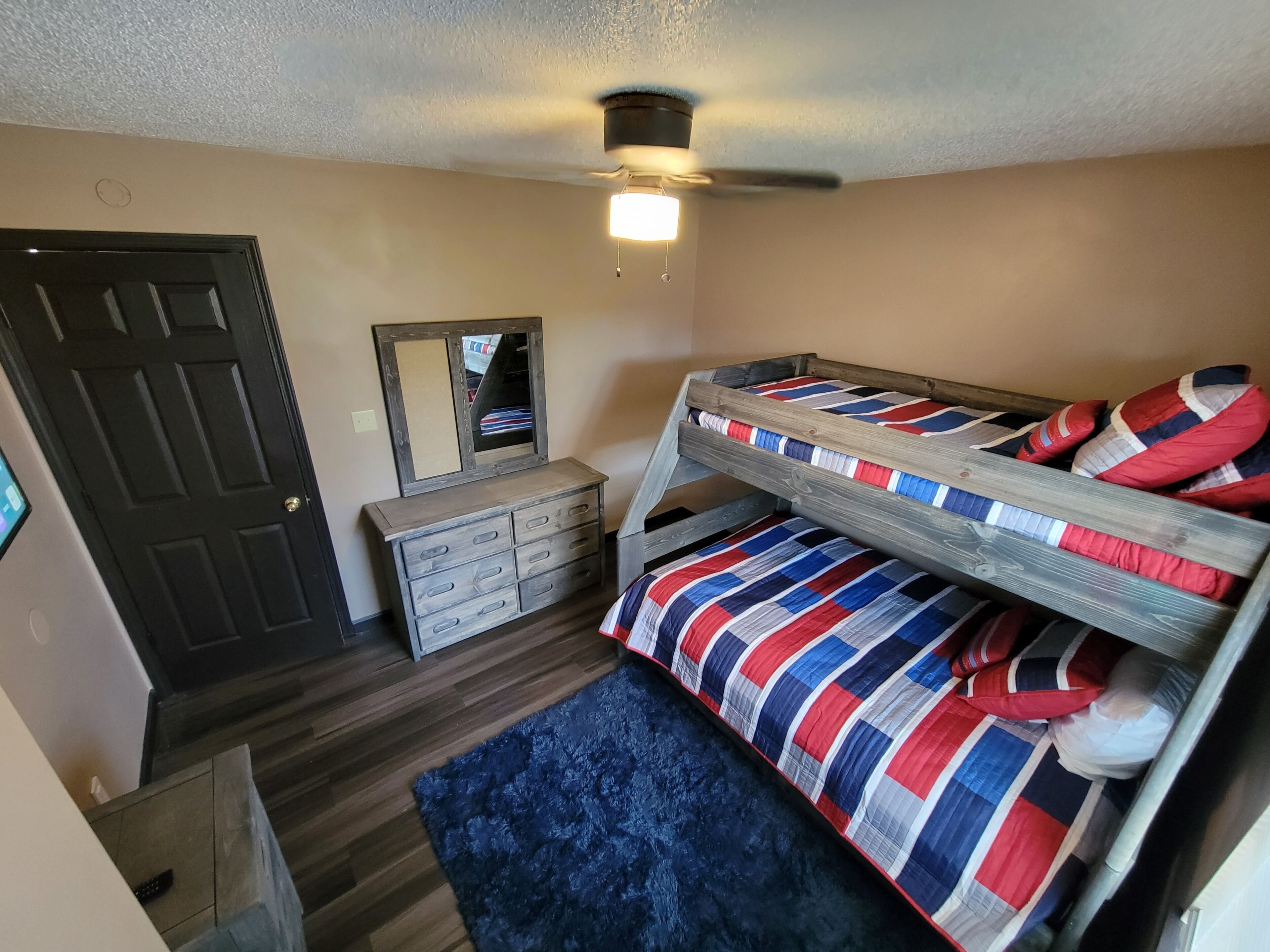 Una habitación con literas, cómoda, espejo y ventilador de techo.