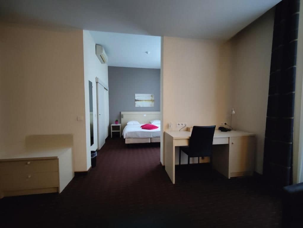 Une chambre d’hôtel comprenant un lit, un bureau, une chaise, une armoire et une petite table.